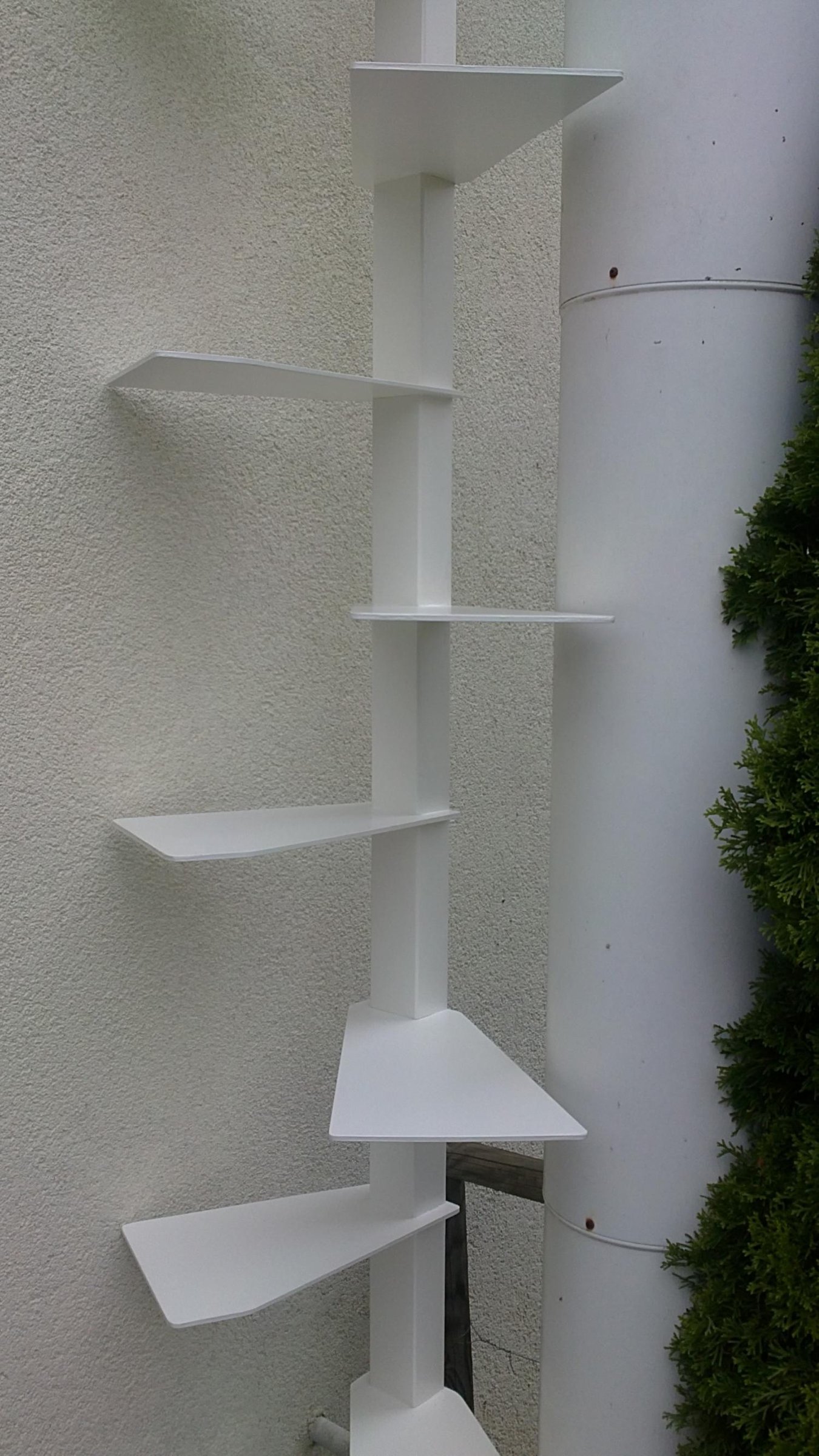 Weisser Katzenbaum mit Tritt-Ablagen am Fallrohr einer Hausfassade