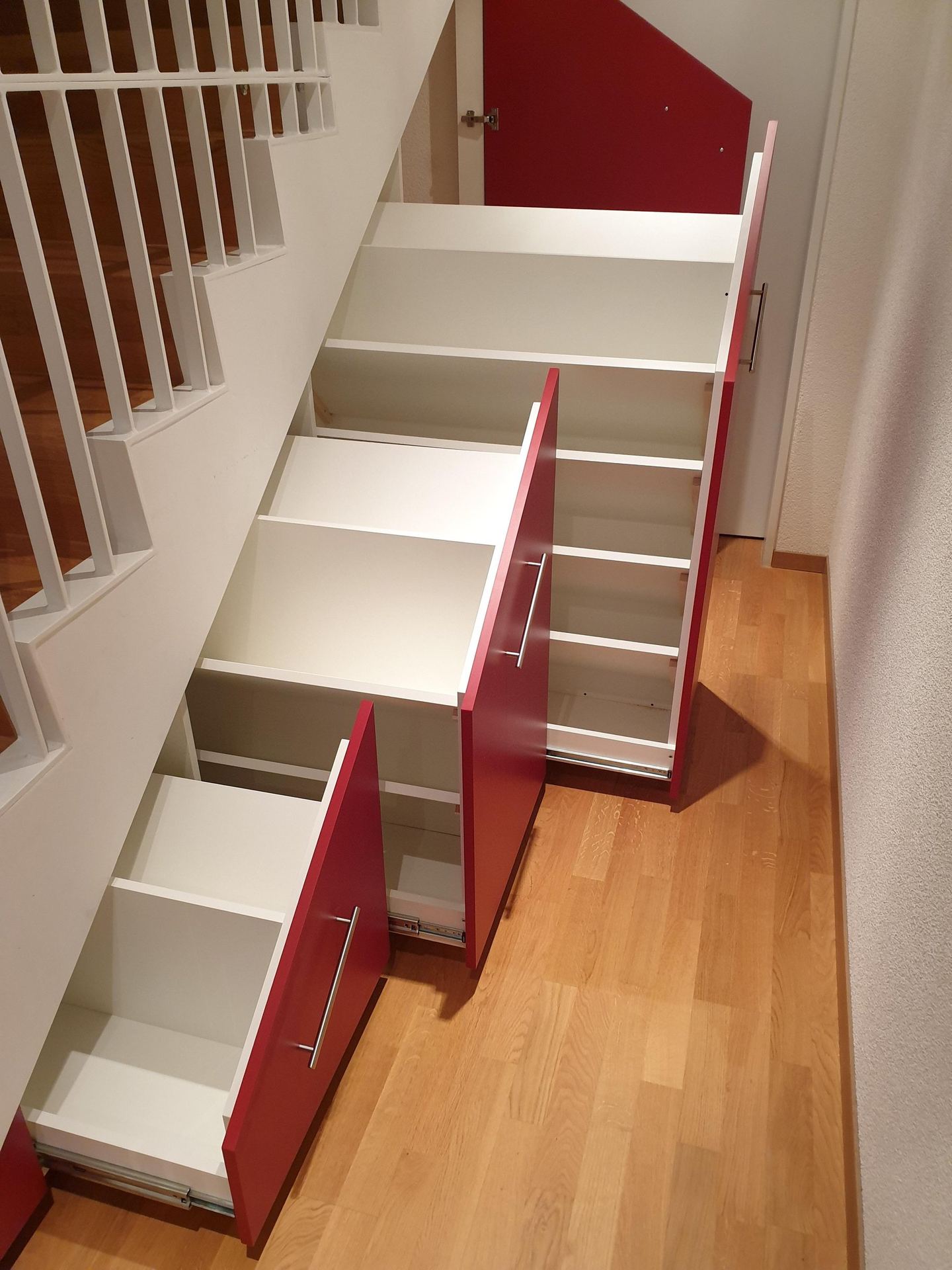Treppenschrank mit roten Fronten und ausziehbaren Schubladen
